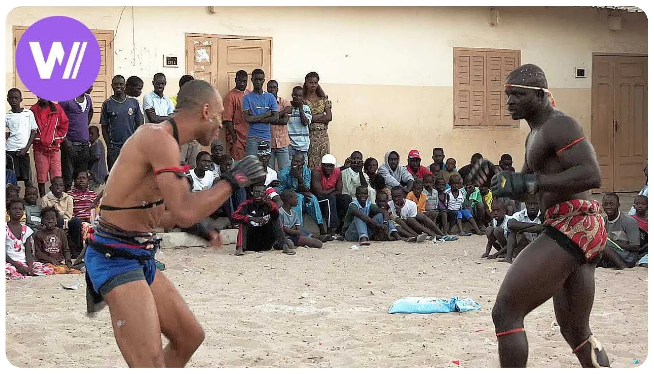 A wocomoCULTURE video thumbnail with the purple W// badge, over a still of a traditional wrestling match.